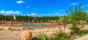 Un espace piscine agrémenté d’une clôture en bois, de chaises longues et d’un ciel d’un bleu limpide.