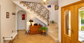 Un escalier orné d’une rampe en métal décorative, une porte en bois et une plante en pot.