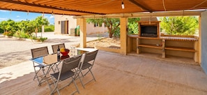 An outdoor patio with a table and chairs, a barbecue grill, and a covered area with a view of the surrounding landscape. - Can Olivaret 419 fantastic finca with private pool, terrace, barbecue and WiFi (Campos)