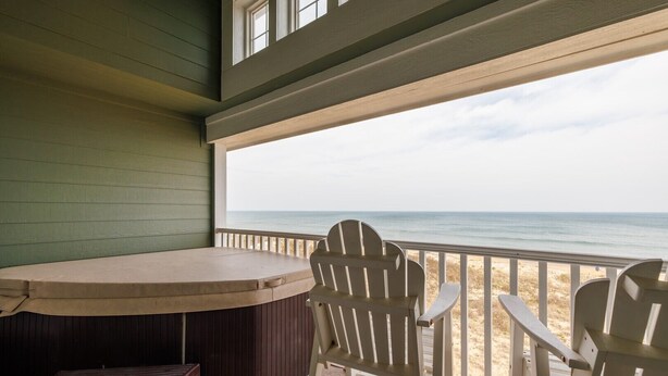 A covered outdoor seating area with a hot tub, chairs, and a view of the beach. - FFR309 - Beach Bliss by FIrst Flight Rentals (Kill Devil Hills)