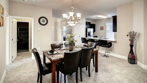 Un espace repas avec une table en marbre, des chaises noires et un lustre.