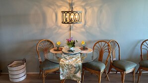 A dining area with a round table, four wicker chairs, a woven basket, and a hanging light fixture. - REDUCED RATES with A/C! 113 Darling little ground floor 1 bed, 1 bath (Lahaina)
