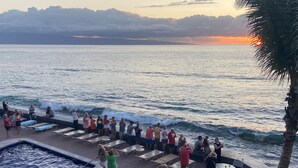 A poolside area with lounge chairs and a hot tub, overlooking the ocean with waves crashing onto the shore. - REDUCED RATES with A/C! 113 Darling little ground floor 1 bed, 1 bath (Lahaina)