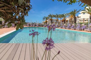 A swimming pool with lounge chairs and palm trees in the background.