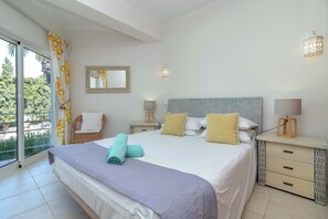 A bedroom with a large bed, two bedside tables, a chair, a mirror, and a view of the outdoors. - Parque nº 17 - Duplex Apartment with amazing Roof Terrace (Ferragudo)