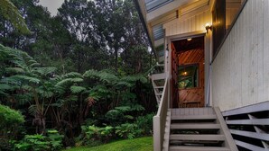 A wooden staircase leading to a room with a window overlooking a lush garden.