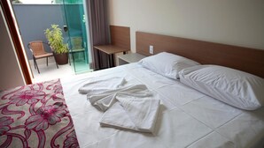 Een hotelkamer met een bed, een stoel, een tafel en een potplant.