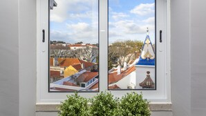 Una finestra che offre doppia vista su un paesaggio urbano, con edifici dai tetti rossi e blu e una chiesa con una cupola azzurra.