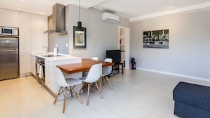 Una cucina moderna con un tavolo da pranzo in legno, sedie bianche e un forno a microonde integrato.