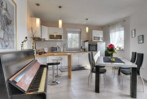 A modern kitchen with a piano, dining table, and chairs.