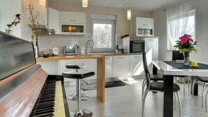 A modern kitchen with a piano, bar stools, and a dining table. - Sunny villa with private pool (Majmajola)
