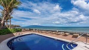 A swimming pool with lounge chairs and a view of the ocean. - Reduced Rates! Charming Ground-Floor 1 BR, 1 BA Condo at 103 Darling with A/C (Lahaina)