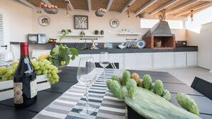 An outdoor kitchen with a brick oven, a table with wine glasses and cacti, and various kitchen items on shelves. - Villa Licia - Villa with pool by the beach (Santa Maria del Focallo)