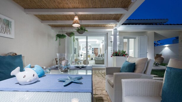 A modern living room with a glass table, wicker furniture, and decorative items like starfish and fish figurines. - Villa Licia - Villa with pool by the beach (Santa Maria del Focallo)
