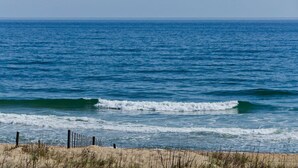 Una playa con olas, una valla y cielo despejado.