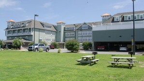 Un edificio de varios pisos con una zona de estacionamiento y mesas de picnic al frente.