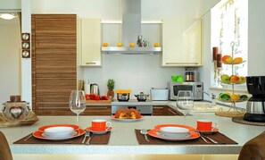 A modern kitchen with wooden cabinets, a central island with orange plates, and a fruit display. - Exclusive villa with private pool, WiFi and BBQ (Buzinija)