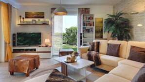 A modern living room with a flat-screen TV, a sofa, a coffee table, and a bookshelf.