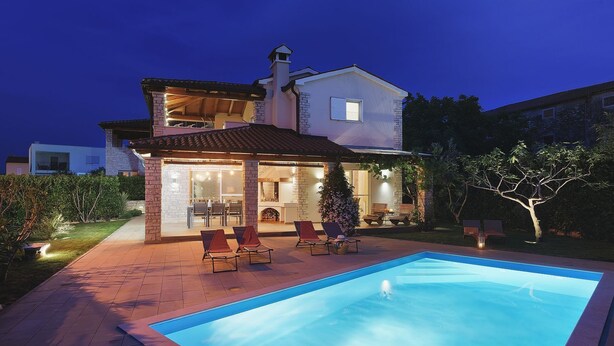 A two-story house with a swimming pool, outdoor seating, and a fireplace.