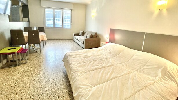 A hotel room with a bed, a sofa, a desk, and chairs. - Themis (Cannes)