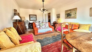 Un salon chaleureux avec un canapé, des fauteuils, une table à manger et un lustre.