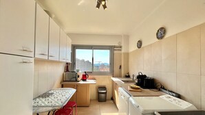 Une cuisine compacte dotée d’une fenêtre, d’un four à micro-ondes, d’un évier, d’une cuisinière et d’un petit coin repas avec une table et des chaises.