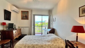 Une chambre à coucher comprenant un lit, une commode, un bureau, une chaise et donnant sur l’extérieur.