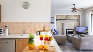 Eine moderne Küche mit Holztischplatte, eine Essecke mit einer Couch und ein Fernseher im Wohnzimmer.