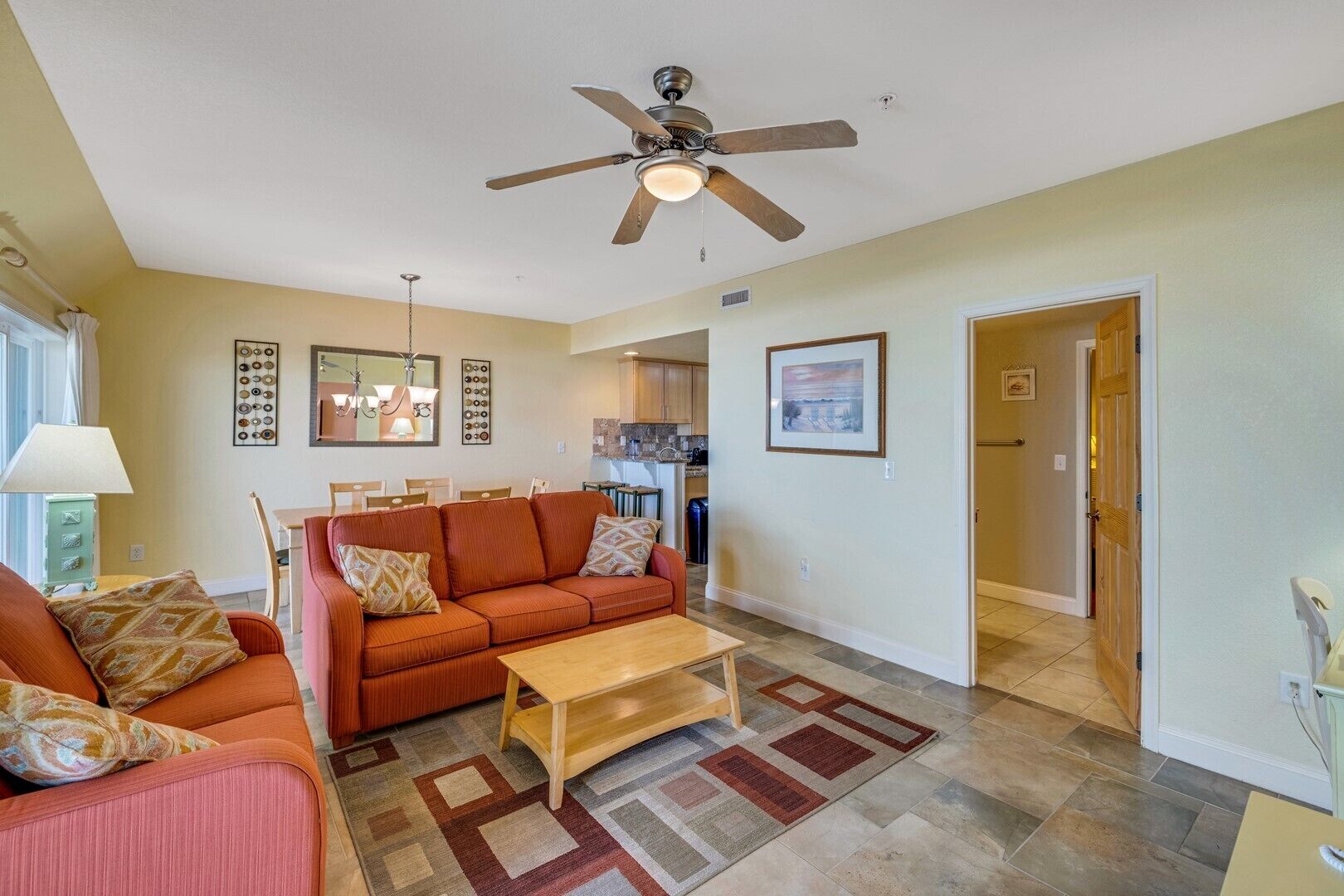 A living room with a sofa, coffee table, and a ceiling fan.