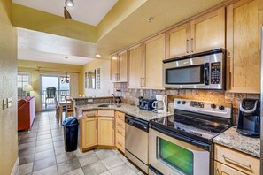 A kitchen with wooden cabinets, a microwave, a stove, and a dishwasher. - FFR211 Atlantic View Retreat by First Flight Rentals (Kill Devil Hills)