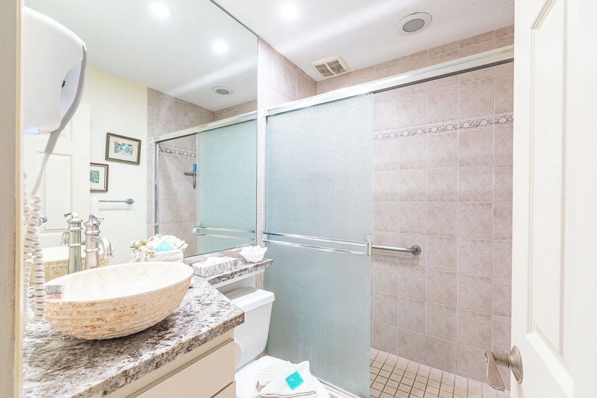 A bathroom with a large oval sink, a glass shower enclosure, and a mirror above the sink.