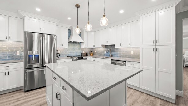 A modern kitchen with white cabinetry, stainless steel appliances, and a large island. - Newly Renovated Beachfront 3 bed, 2 bath at Sanibel Moorings #711 (Sanibel)
