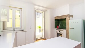 A modern kitchen with white cabinetry, a green tiled backsplash, and a white refrigerator. - Pateo Boaventura in Bairro Alto (Lisbon)
