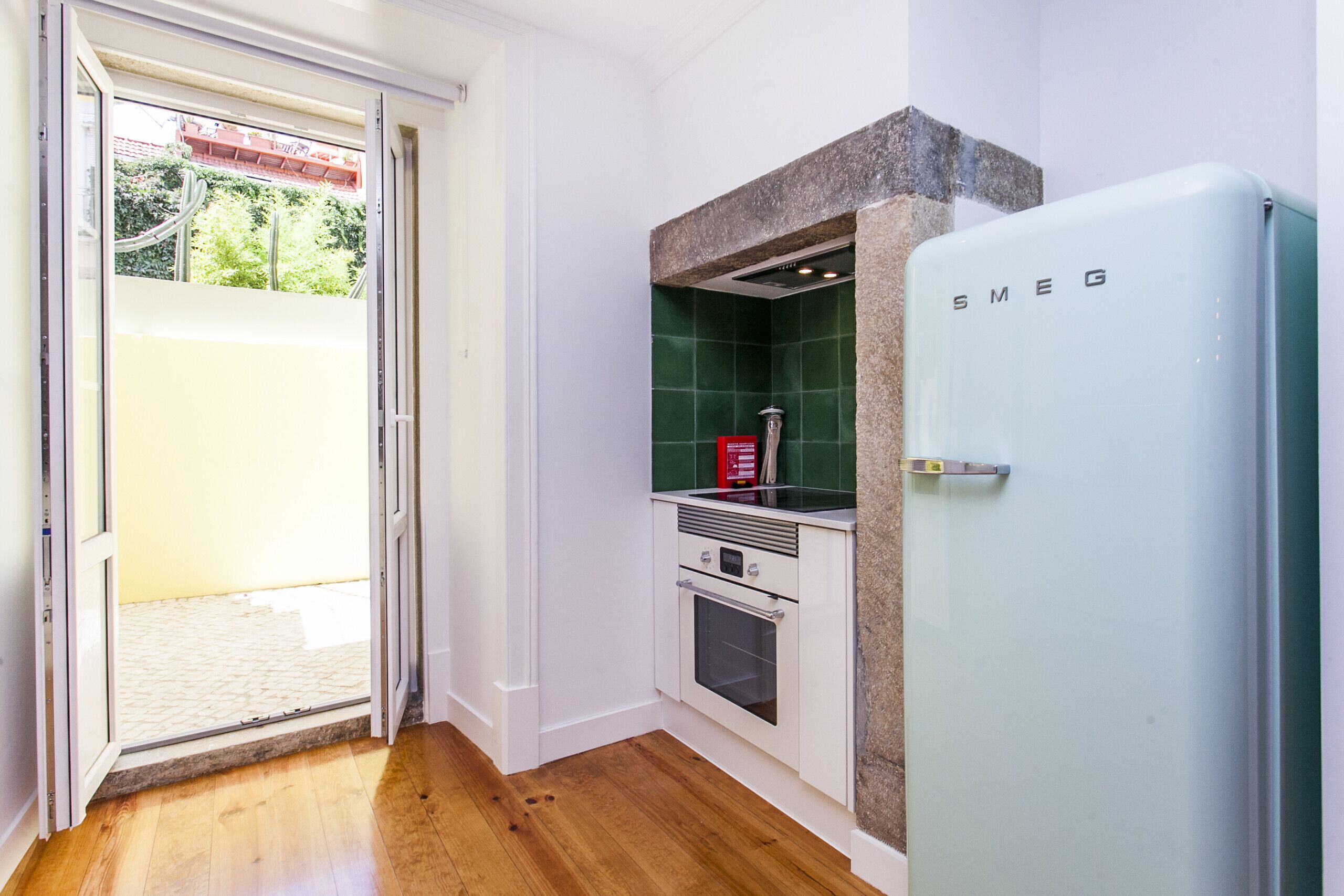 A compact kitchen with a white refrigerator, a built-in oven, and a green tiled backsplash.