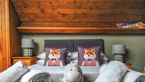 Een bed met twee kussens met een vosmotief, een lamp en een tijdschrift op een houten plank.