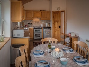Un coin repas avec une table ronde dressée pour quatre personnes, agrémentée d’assiettes, de couverts et de verres.