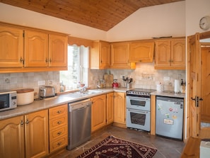 Une cuisine avec des meubles de rangement en bois, un lave-vaisselle, une cuisinière et un réfrigérateur.