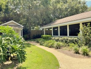 A house with a covered patio area, a lawn, and various shrubs.