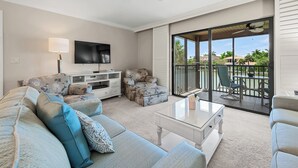 A spacious living room with a flat-screen TV, a ceiling fan, and a balcony with outdoor seating. - Waterfront Dock View 2 bed, 2 bath at Sanibel Moorings #1332 (Sanibel)