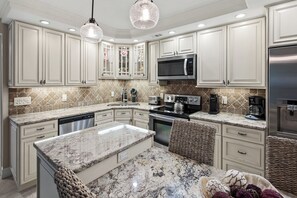 A kitchen with white cabinetry, granite countertops, a stainless steel refrigerator, and a built-in microwave. - Waterfront Dock View 2 bed, 2 bath at Sanibel Moorings #1332 (Sanibel)