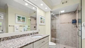 A bathroom with a granite countertop, a white sink, a toilet, and a glass-enclosed shower. - Waterfront Dock View 2 bed, 2 bath at Sanibel Moorings #1332 (Sanibel)