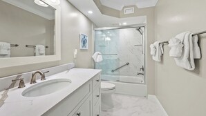 Une salle de bain moderne avec un grand miroir, un lavabo, des toilettes et une douche à parois de verre.