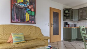 Un soggiorno con divano, tavolino in vetro e un quadro appeso al muro.