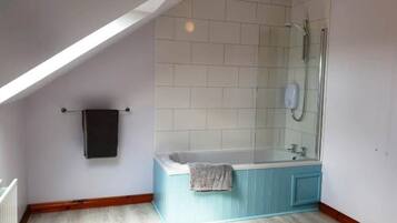 Una habitación con techo inclinado, una bañera y una ducha.