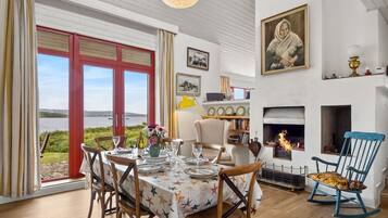 A dining area with a table set for four, a fireplace, and a view of the outdoors.