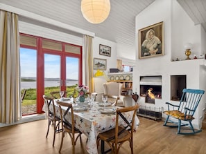 A dining area with a table set for four, a fireplace, and a view of the outdoors.
