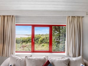 A bedroom with a large window, a bed with pillows, and curtains.