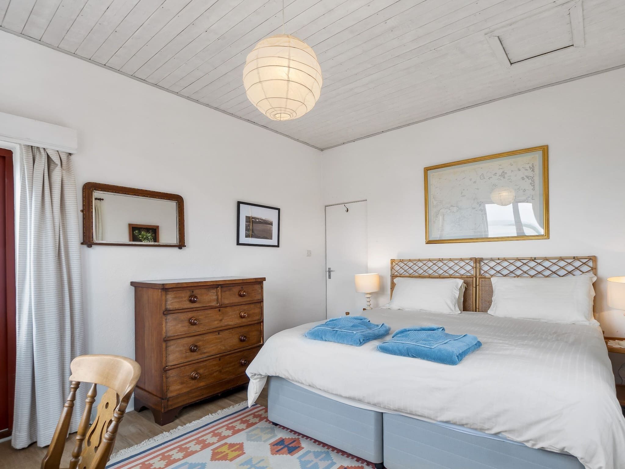 Une chambre à coucher comprenant un lit, une commode, une chaise et un luminaire suspendu.