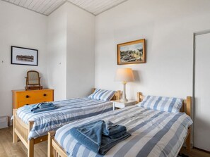 A bedroom with two beds, a nightstand with a lamp, a dresser, and a framed picture on the wall.