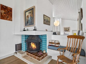A cozy room with a fireplace, a wooden chair, and a shelf with various items.